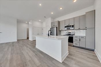 A modern kitchen with a white island and wooden floors.